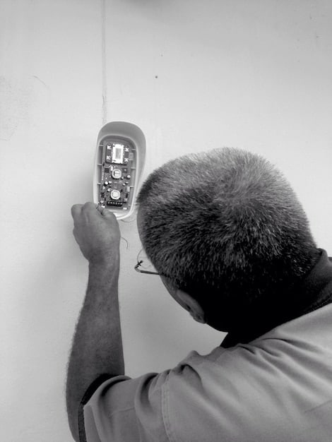 A close-up shot of a technician installing a wireless security camera on a wall, highlighting the professional tools and precision involved in the process. The technician is wearing a uniform, emphasizing their expertise.