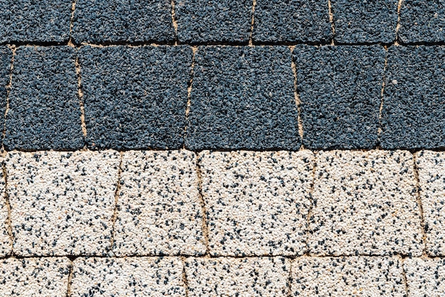 Close-up of different paving materials for driveways, including block paving, resin-bound gravel, and tarmac. The image highlights the texture and colour variations available, set against a backdrop of a residential garden.