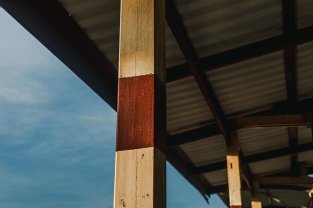A partially constructed wooden shed frame, showcasing the vertical studs, horizontal top and bottom plates, and diagonal bracing. The frame sits on a leveled gravel base, and tools like a level, measuring tape, and hammer are visible nearby. The background includes a garden with various plants and shrubs.