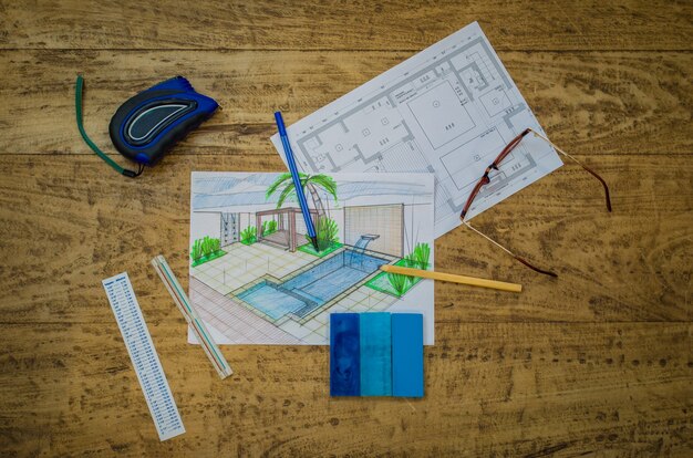 A blueprint of a conservatory design, showing detailed measurements and structural plans, with notes on materials and dimensions, overlaid on a table with architectural tools and samples.