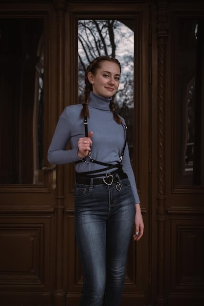 A woman with an hourglass figure wearing a pair of high-waisted, dark-wash Shein skinny jeans, a tucked-in white fitted blouse, and a stylish brown belt, confidently posing in a vibrant urban setting.