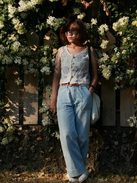 A woman with an apple body type wearing high-waisted, dark-wash Shein straight-leg jeans, a flowy patterned tunic, and delicate necklace, looking stylish and comfortable in a casual outdoor setting.
