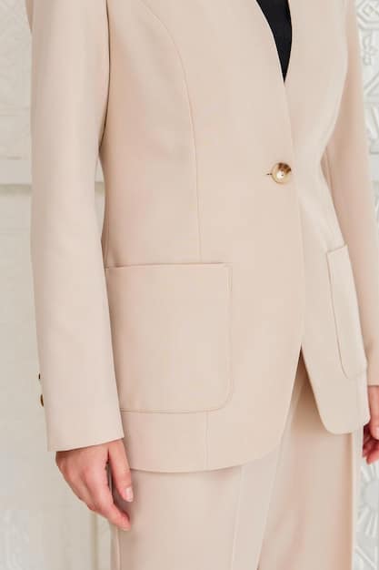 A close-up of a women's beige oversized blazer, showing texture and detail, suitable for office wear.