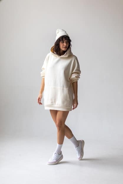 A full-body shot of a stylish woman in a neutral-toned oversized Shein loungewear set (hoodie and joggers), accessorized with delicate gold jewelry and clean white sneakers, walking in an urban setting.