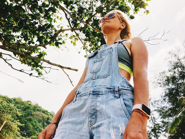 A young adult in an urban setting, wearing wide-leg recycled denim jeans, an organic cotton graphic tee, and a recycled polyester utility vest.