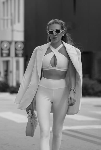 A stylish model showcasing a monochromatic athleisure outfit from Shein's 2025 collection, entirely in shades of earthy olive green, featuring high-waisted leggings, a matching sports bra, an open oversized button-down shirt, and chunky white sneakers, captured in a bright, natural light.