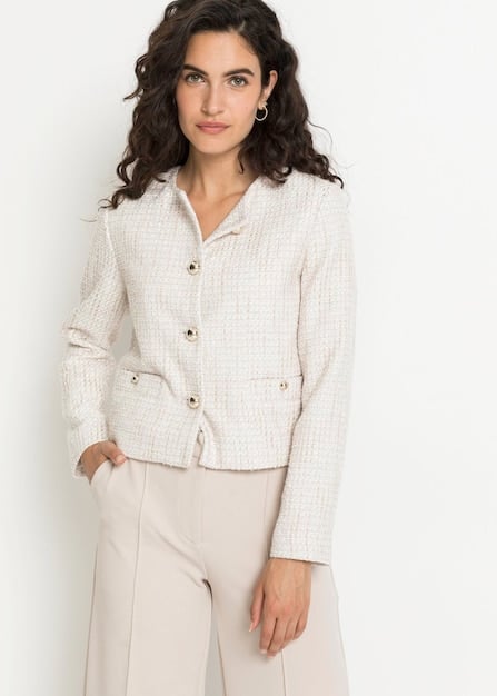 A woman expertly layering a Shein white button-down shirt beneath a neutral knit vest, paired with tailored trousers, demonstrating sophisticated layering techniques for an elevated look.