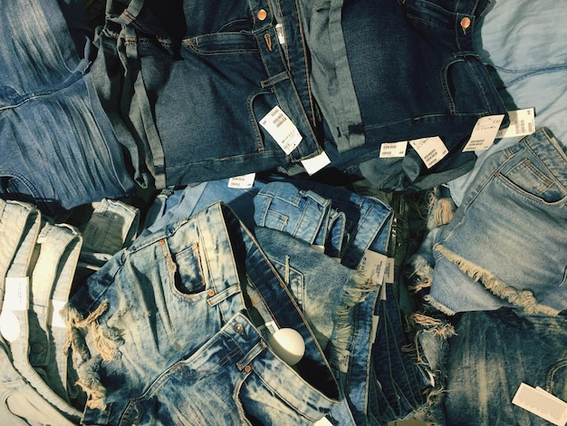 A flat lay of several pairs of Shein denim jeans, showcasing a range of washes from dark indigo to light bleached, with various distressing details like rips, frayed hems, and subtle fading.