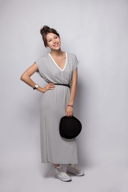 A pear-shaped woman in a vibrant, off-the-shoulder top and dark A-line skirt, with a stylish belt accentuating her waist, against a minimalist studio background.